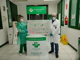 Dous empregados de Fraternidad-Muprespa mostrando un cartel de agradecemento ao colectivo Somos Martos