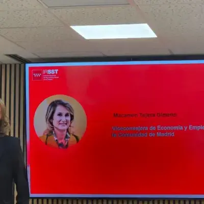 Mujer con micrófono frente a pantalla roja con foto y texto