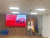 Mujer en un podio ante una pantalla de Galicia Calidade y banderas