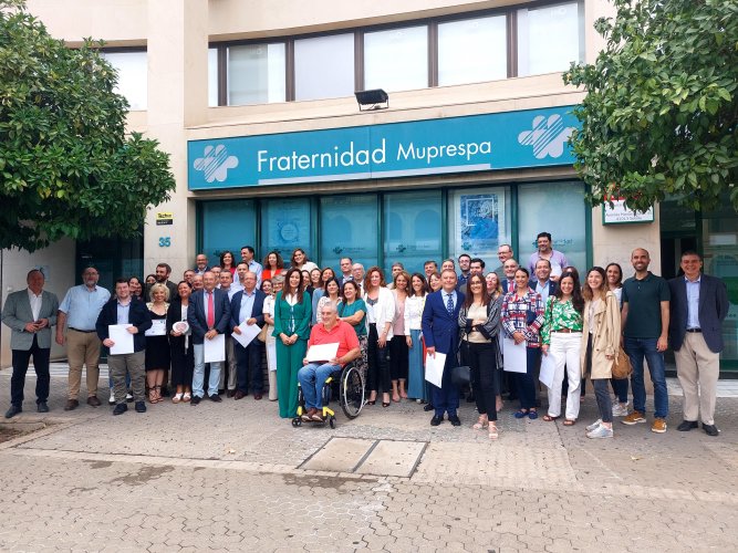 Foto de grupo de los asistentes al acto, ante la fachada de la dirección Provincial de Fraternidad-Muprespa en Sevilla 